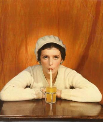 Woman in sweater and white beret drinking with a straw, by Egidio Scaioni